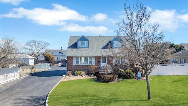 cape cod-style house featuring aphalt driveway, fence, brick siding, and a front lawn