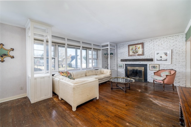 living area with brick wall, a fireplace, baseboards, and hardwood / wood-style floors