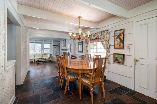 dining area with an inviting chandelier, stone tile floors, and beamed ceiling