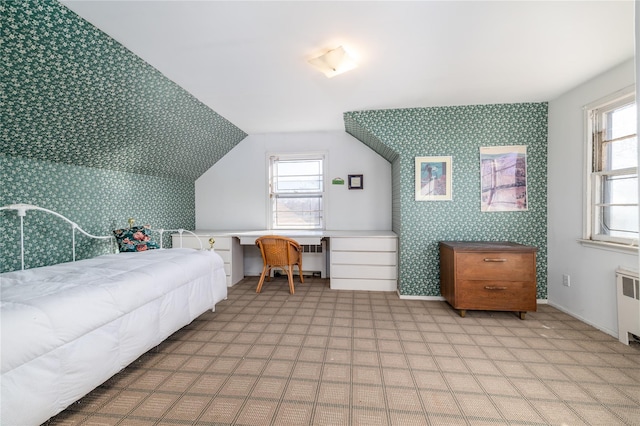 bedroom with radiator heating unit, built in study area, multiple windows, and wallpapered walls