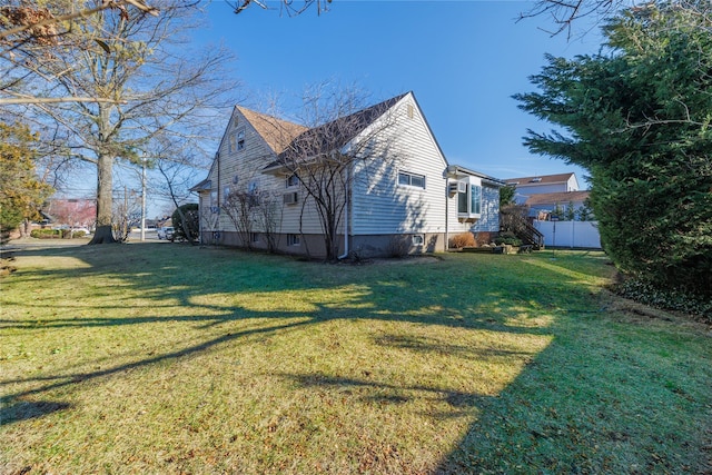 view of side of property featuring fence and a lawn