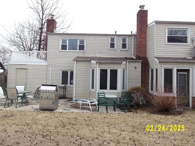 back of house with a chimney, a patio area, and a lawn