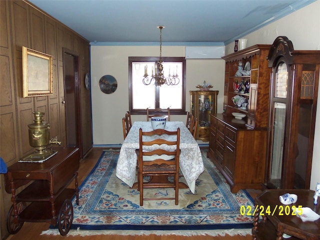 dining room with ornamental molding, wood finished floors, and an inviting chandelier