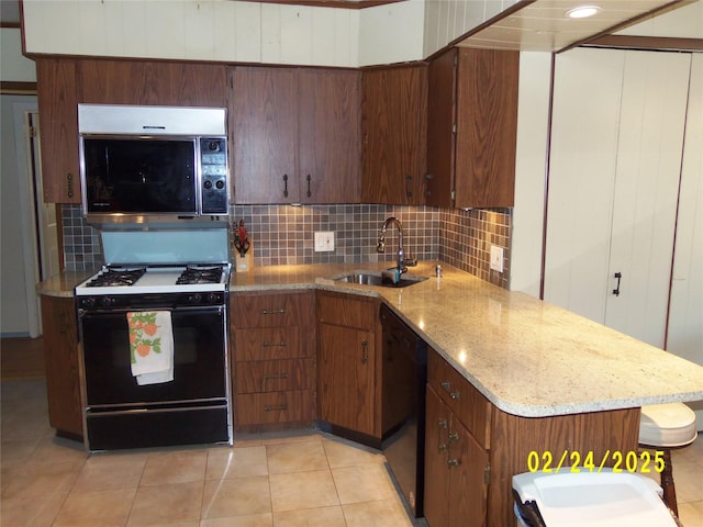 kitchen featuring a sink, black dishwasher, backsplash, light stone countertops, and gas range