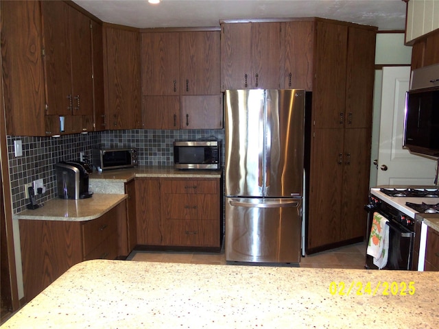 kitchen featuring a toaster, appliances with stainless steel finishes, light tile patterned flooring, and tasteful backsplash