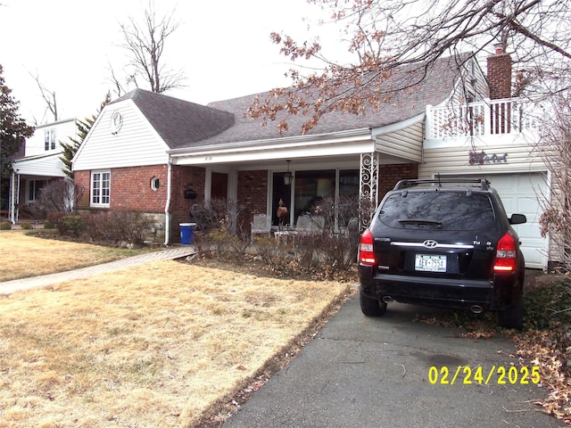 view of front of house featuring covered porch, roof with shingles, a front lawn, and brick siding