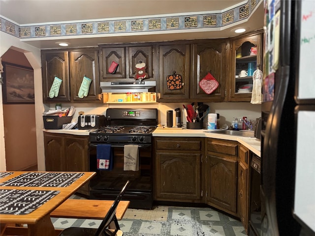 kitchen with light floors, under cabinet range hood, dark brown cabinets, light countertops, and black appliances