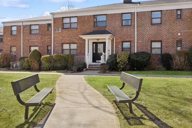 view of front of home with a chimney, a front lawn, and brick siding