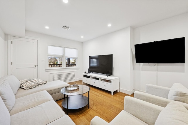 living room featuring light wood-style floors, recessed lighting, visible vents, and baseboards