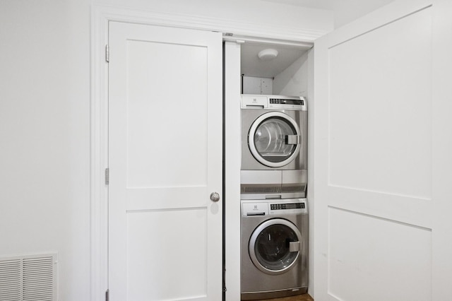 washroom with laundry area, stacked washing maching and dryer, and visible vents