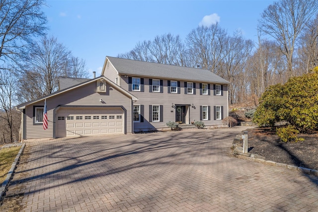 colonial-style house featuring decorative driveway and an attached garage