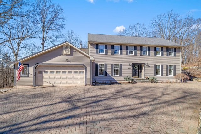 colonial house featuring decorative driveway and an attached garage