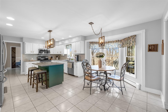 kitchen featuring backsplash, a center island, white cabinets, stainless steel appliances, and a sink