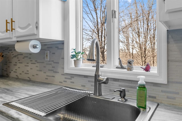 details with decorative backsplash, light countertops, white cabinets, and a sink