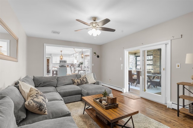 living room featuring a wealth of natural light, visible vents, wood finished floors, and a baseboard radiator