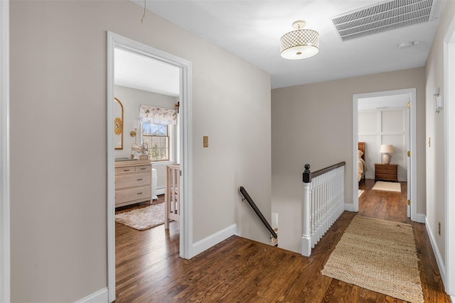 hallway featuring visible vents, an upstairs landing, baseboards, and wood finished floors