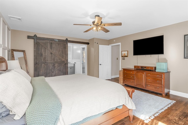 bedroom featuring visible vents, wood finished floors, a barn door, baseboards, and ceiling fan