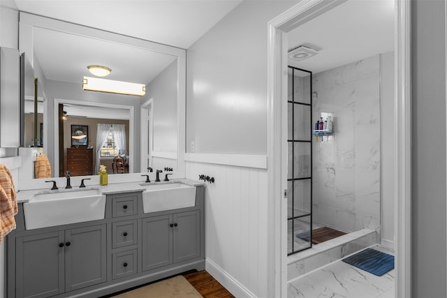 full bathroom with a marble finish shower, marble finish floor, double vanity, and a sink