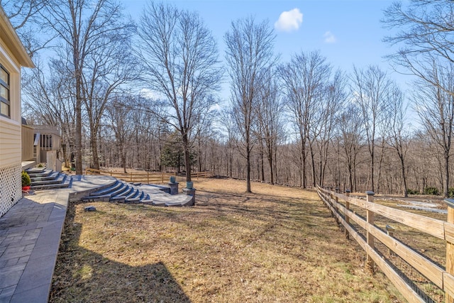 view of yard with a wooded view and fence