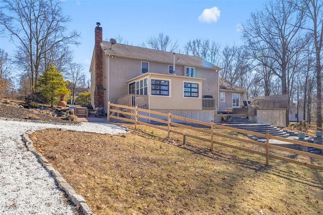 back of house featuring a wooden deck, stairway, fence, and a chimney