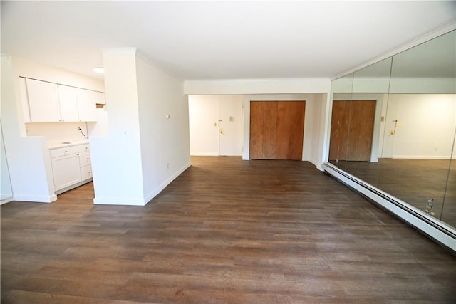 unfurnished room with a baseboard heating unit, crown molding, dark wood finished floors, and baseboards