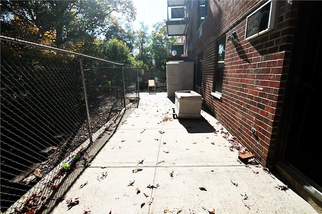 view of property exterior with fence, a patio, and brick siding