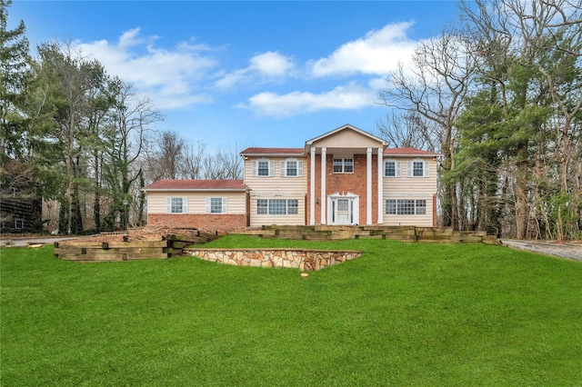 greek revival house featuring brick siding and a front yard