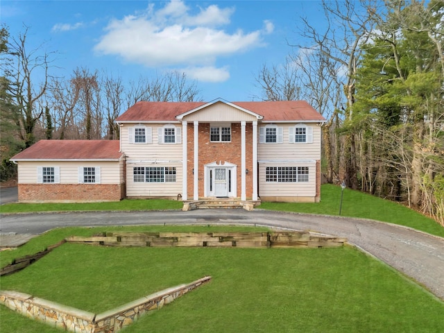 greek revival house with driveway, a front lawn, and brick siding