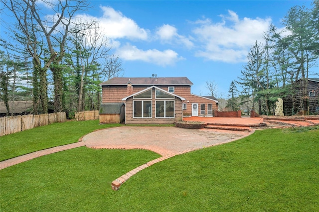 rear view of property with a patio, a lawn, and fence