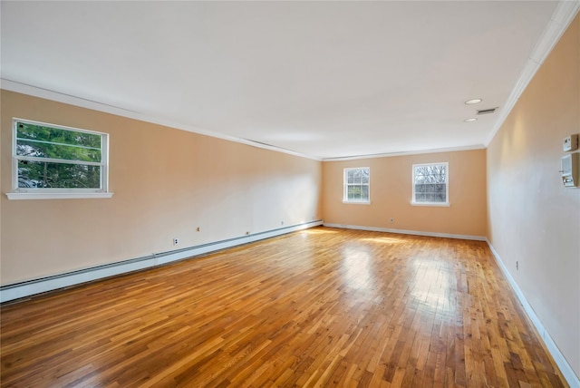 empty room featuring light wood-style floors, a baseboard radiator, crown molding, and baseboards