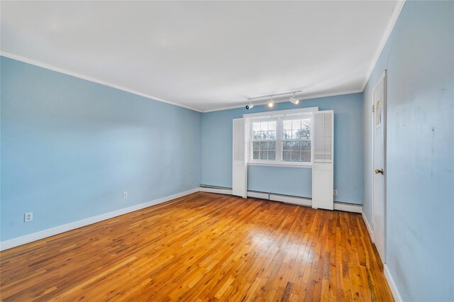 unfurnished room with a baseboard radiator, wood-type flooring, baseboards, and crown molding