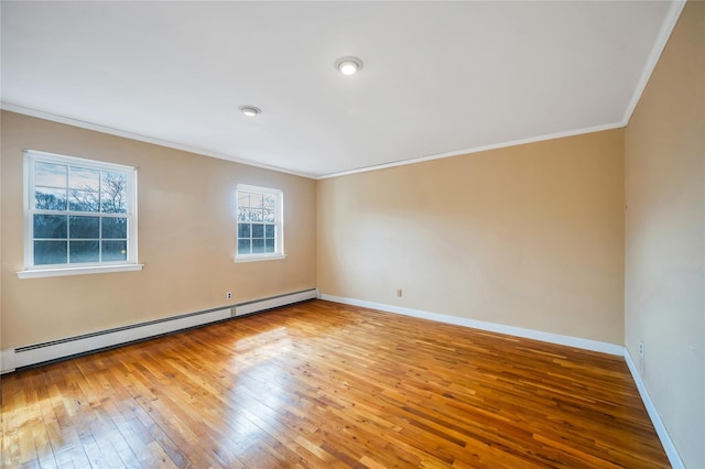 empty room with a baseboard radiator, baseboards, wood-type flooring, and crown molding