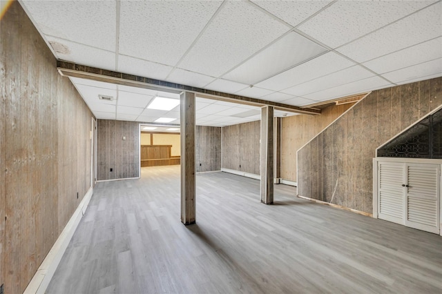 finished below grade area featuring wood walls, wood finished floors, and a paneled ceiling