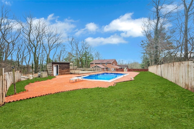 view of swimming pool with a fenced in pool, a fenced backyard, an outbuilding, a yard, and a diving board