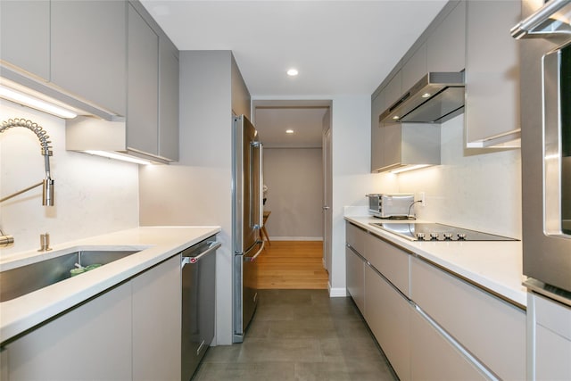 kitchen with recessed lighting, a sink, wall chimney range hood, appliances with stainless steel finishes, and gray cabinets