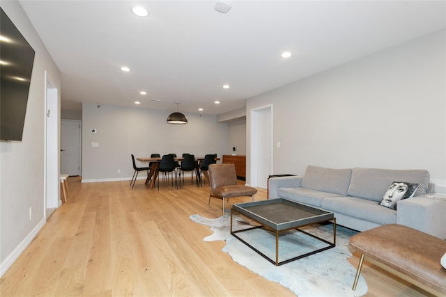 living area featuring baseboards, light wood finished floors, and recessed lighting