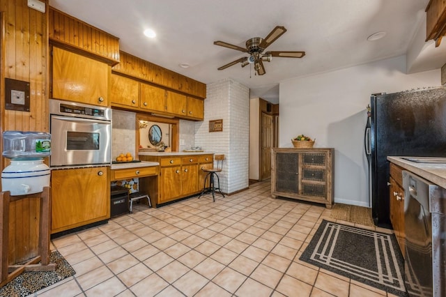 kitchen with ceiling fan, brown cabinets, stainless steel appliances, light countertops, and light tile patterned flooring