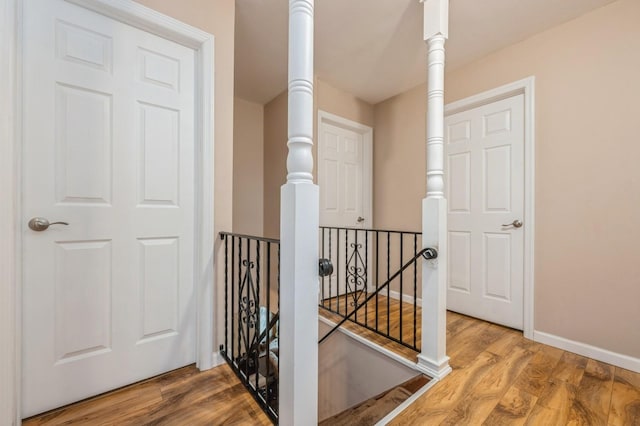 hall with baseboards, an upstairs landing, and wood finished floors