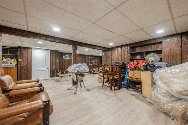 finished basement with recessed lighting, a drop ceiling, wood finished floors, and wooden walls