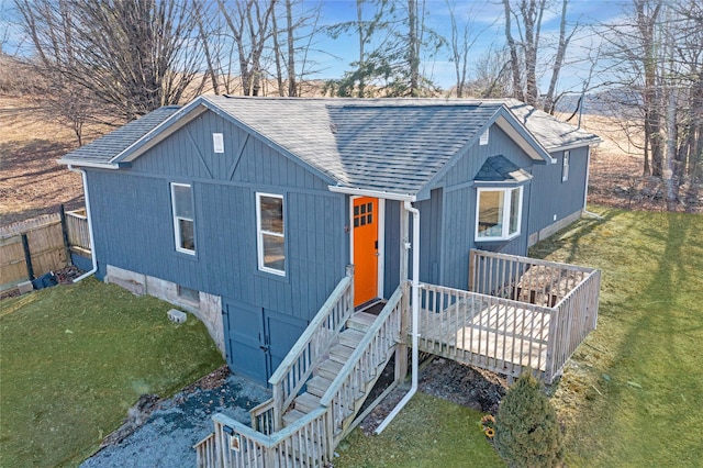 view of front facade featuring a front yard, roof with shingles, and fence