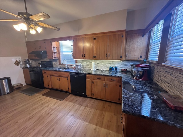 kitchen with light wood-style flooring, under cabinet range hood, decorative backsplash, black appliances, and brown cabinetry