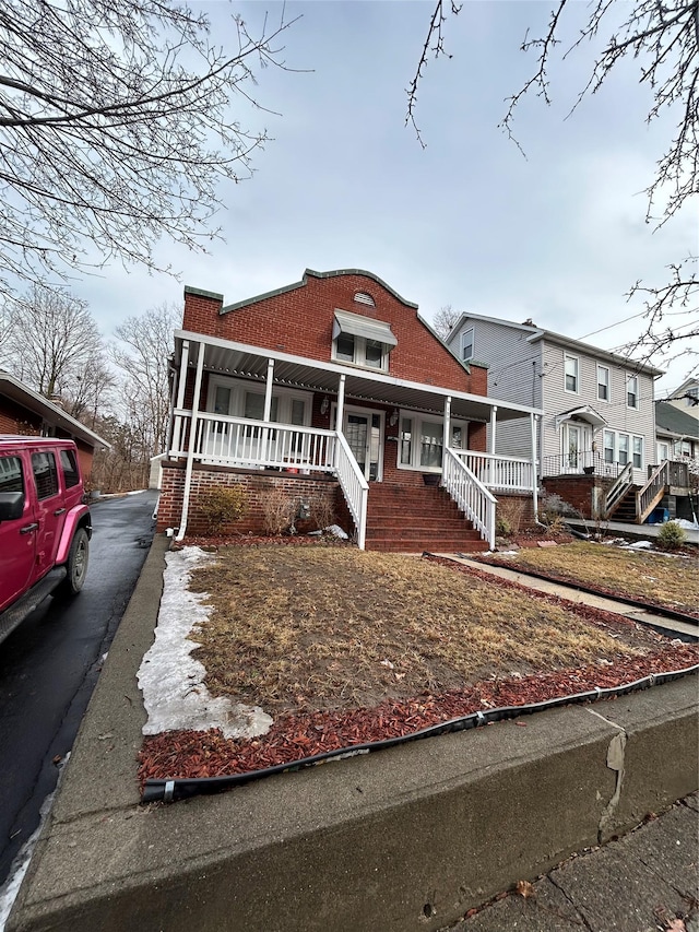 view of front of home featuring covered porch and brick siding