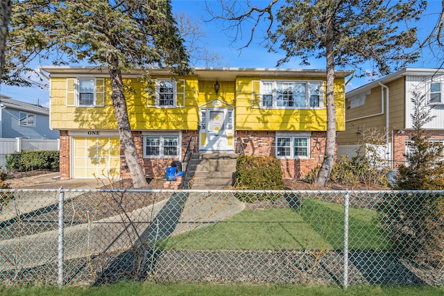 raised ranch with a fenced front yard, brick siding, and a garage