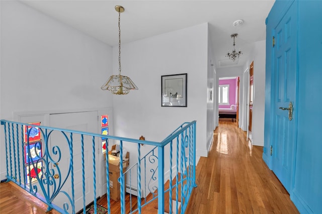 corridor featuring an upstairs landing, wood finished floors, baseboards, and baseboard heating