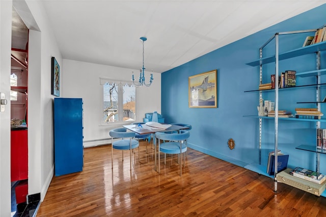 dining area with a baseboard radiator, a notable chandelier, baseboards, and wood finished floors