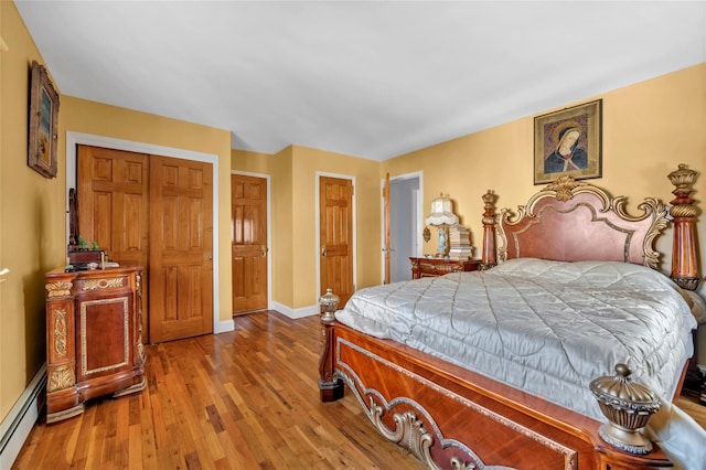 bedroom with a baseboard radiator, wood finished floors, and baseboards