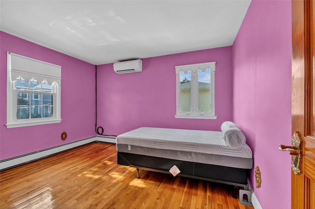 bedroom featuring a baseboard heating unit, wood finished floors, and a wall mounted AC