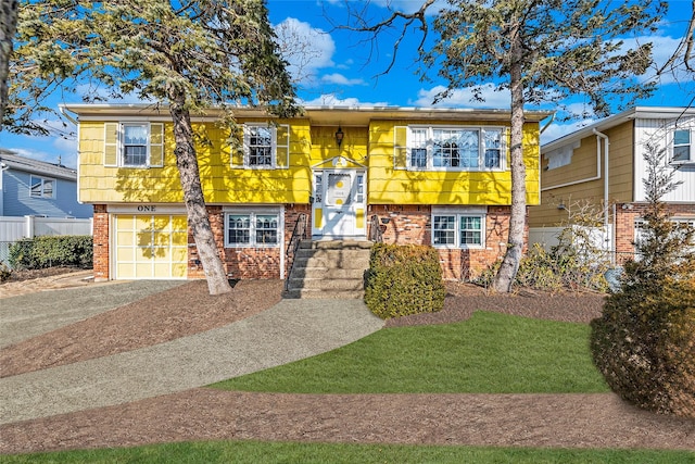 split foyer home with a garage, brick siding, and driveway