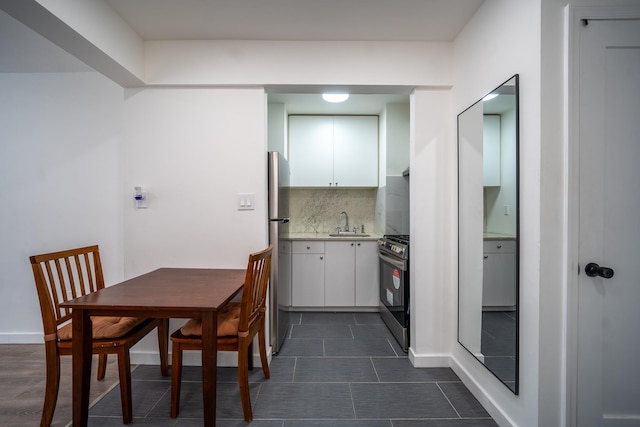 kitchen featuring tasteful backsplash, white cabinets, stainless steel appliances, light countertops, and a sink