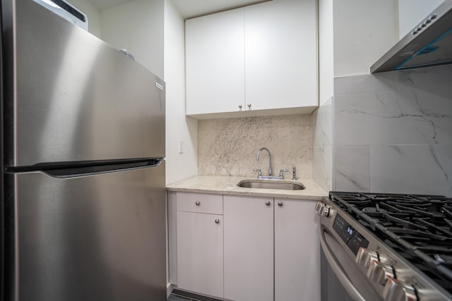 kitchen featuring stainless steel appliances, decorative backsplash, white cabinets, a sink, and under cabinet range hood